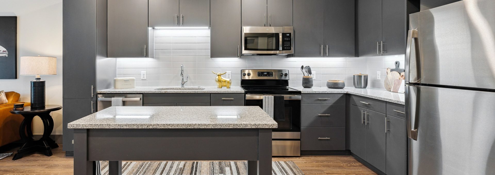 a kitchen with stainless steel appliances and gray cabinets at The BroadVue